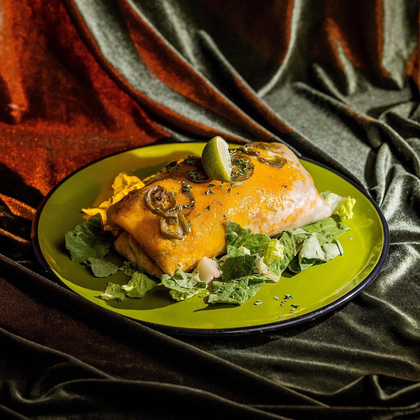 Burrito on green plate surrounded by lettuce