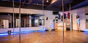 Open room with mirrors in background and poles for dancing classes in foreground