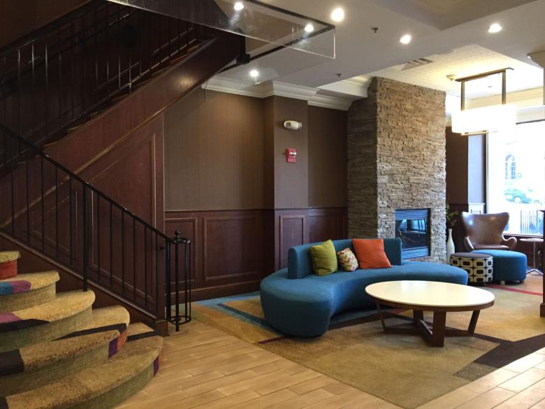 Interior view of the Fairfield Inn and Suites lobby, a coffee table and lounge chairs are in focus. 
