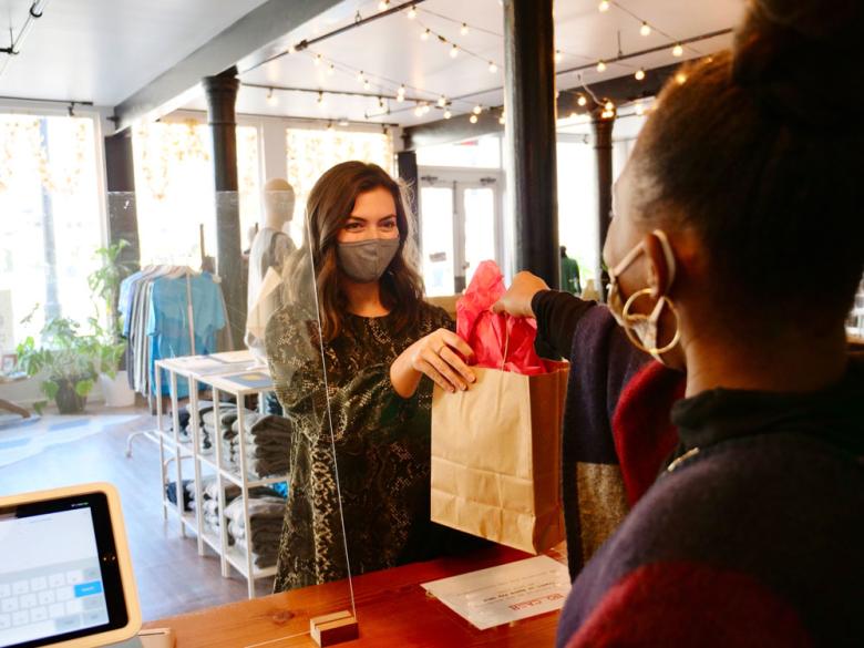 Shopper receiving her purchase in a gift bag over the counter from the employee