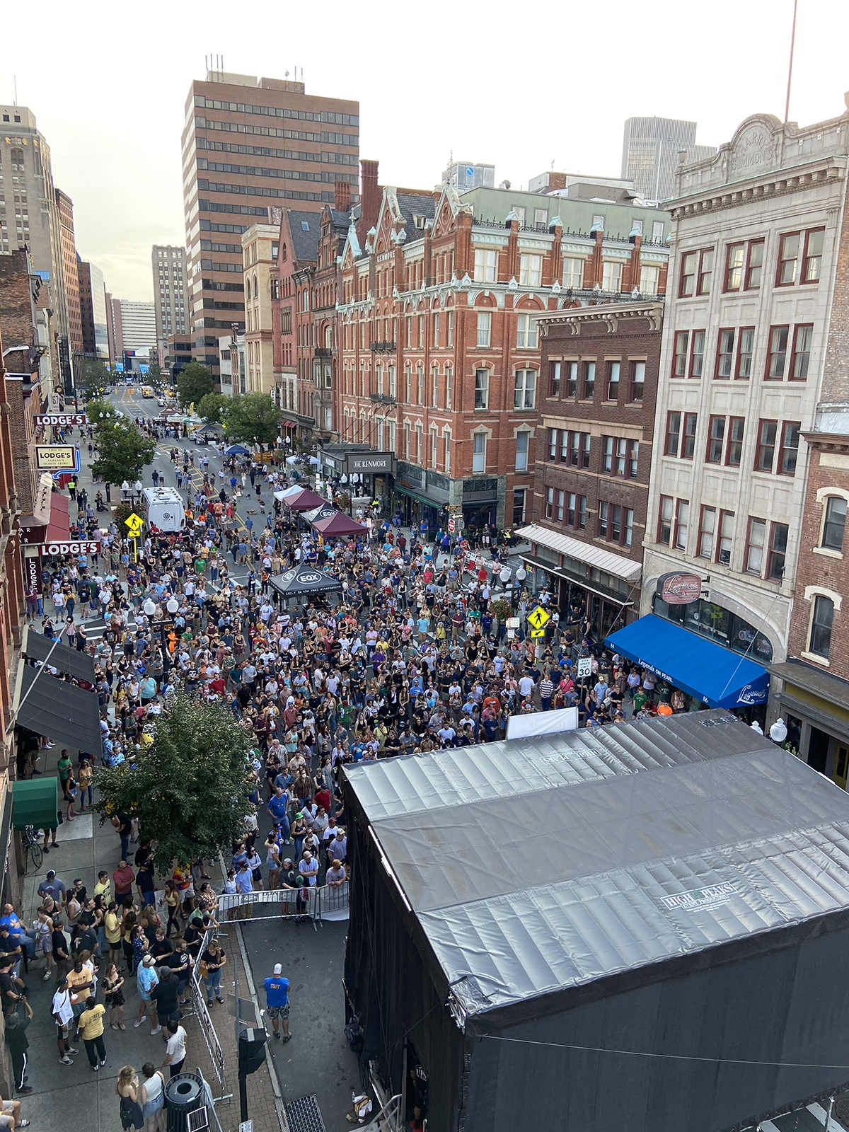 Roof of stage shown with on-street crowd facing the stage