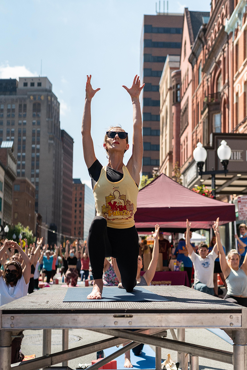 Woman leads yoga class from stage
