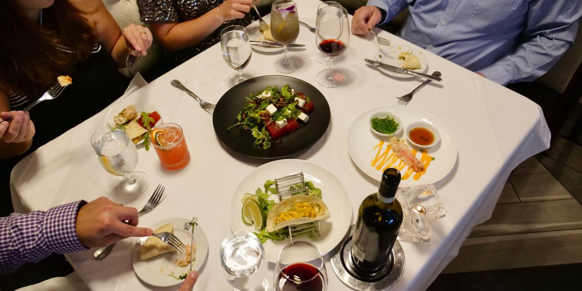 People sit at dining room table full of food and drink