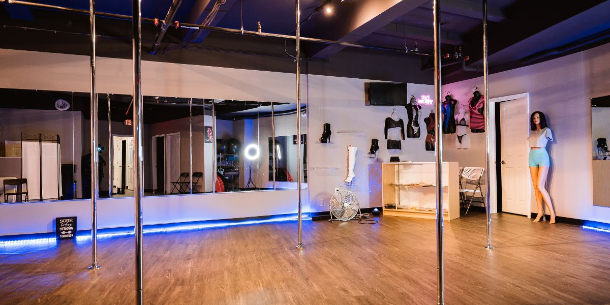 Open room with mirrors in background and poles for dancing classes in foreground