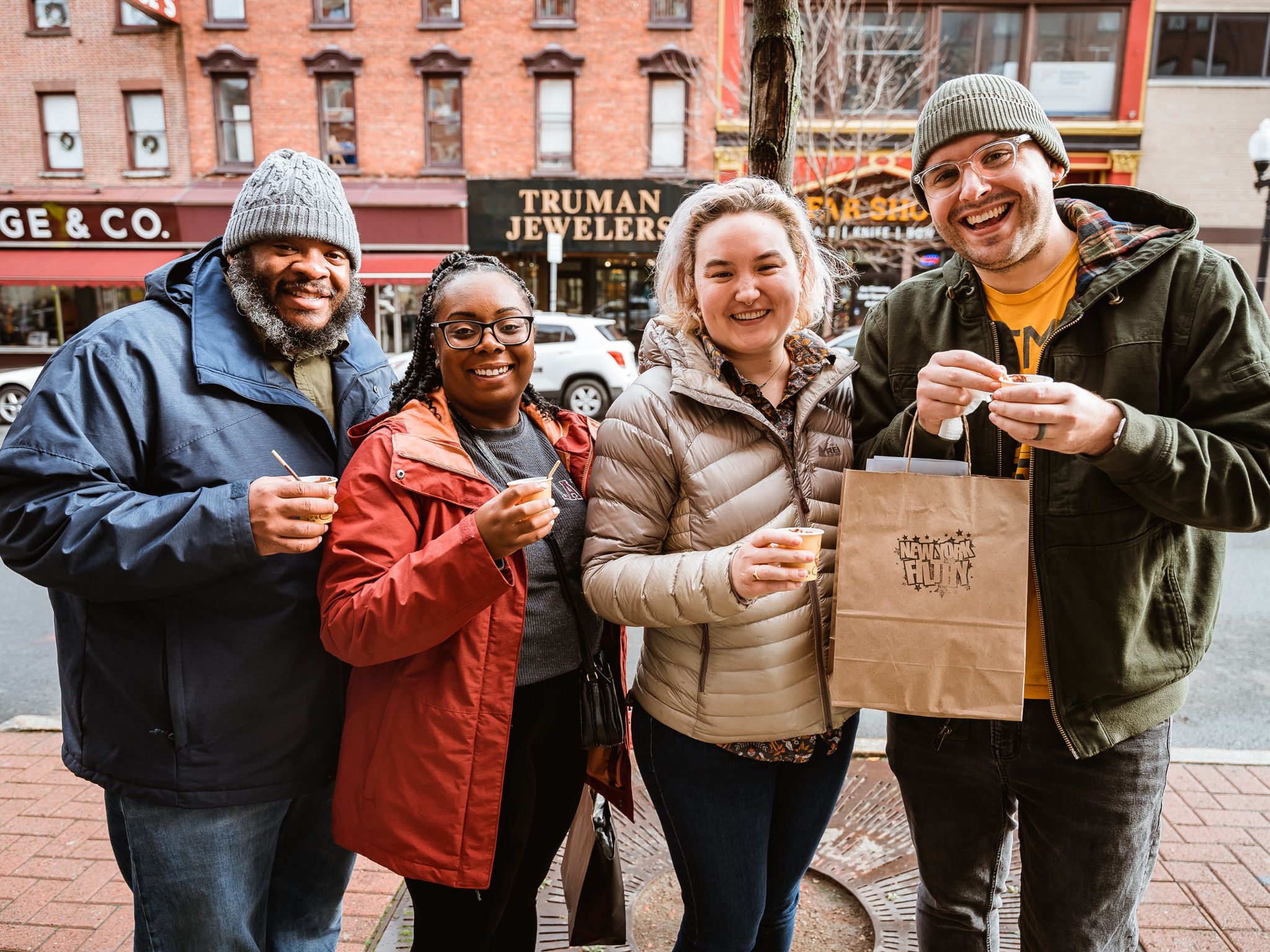 Four people stand on street holding bags