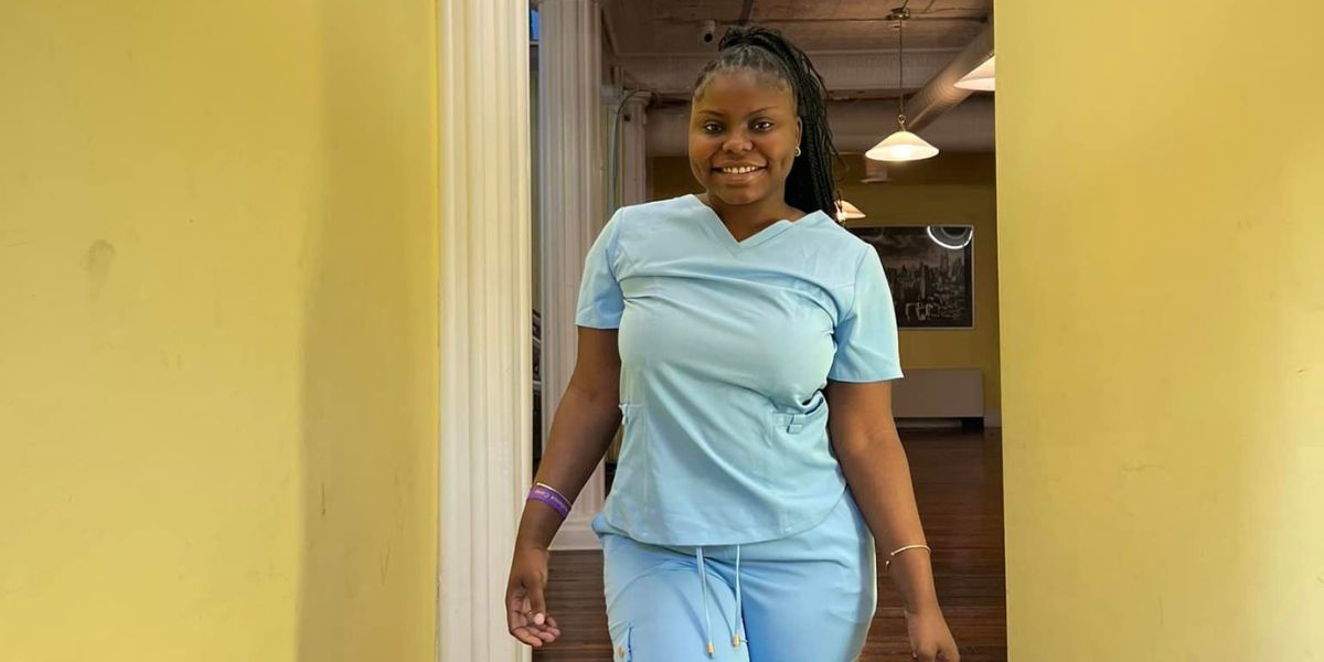 Woman stands in hallway modeling scrubs