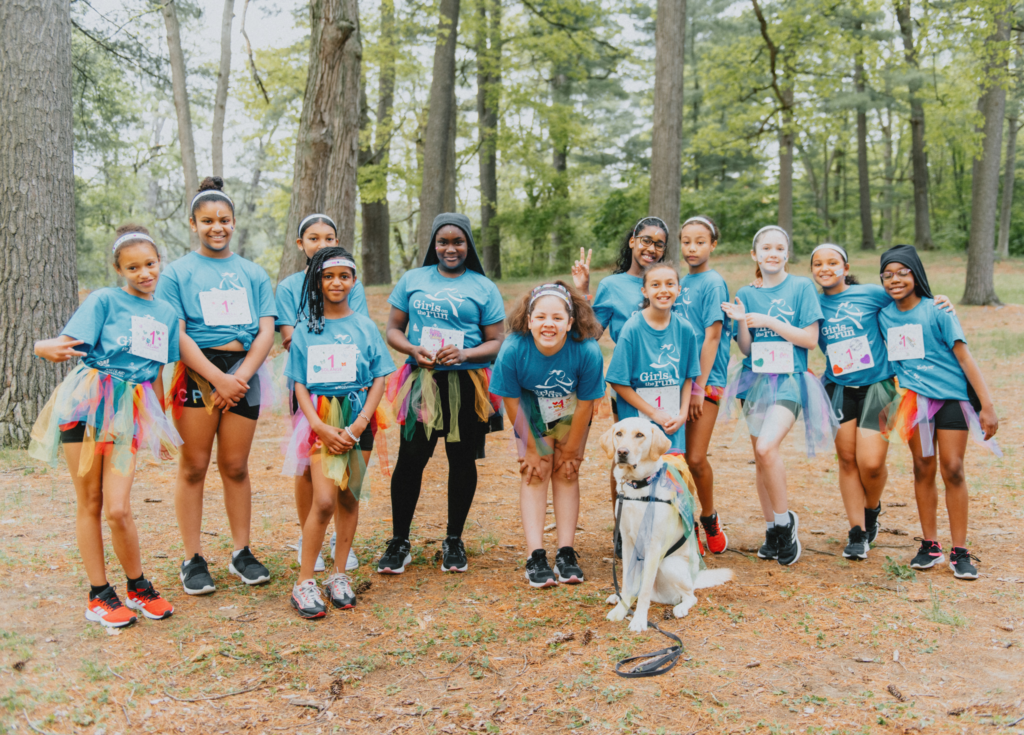 Girls stand in line with matching shirts and running numbers