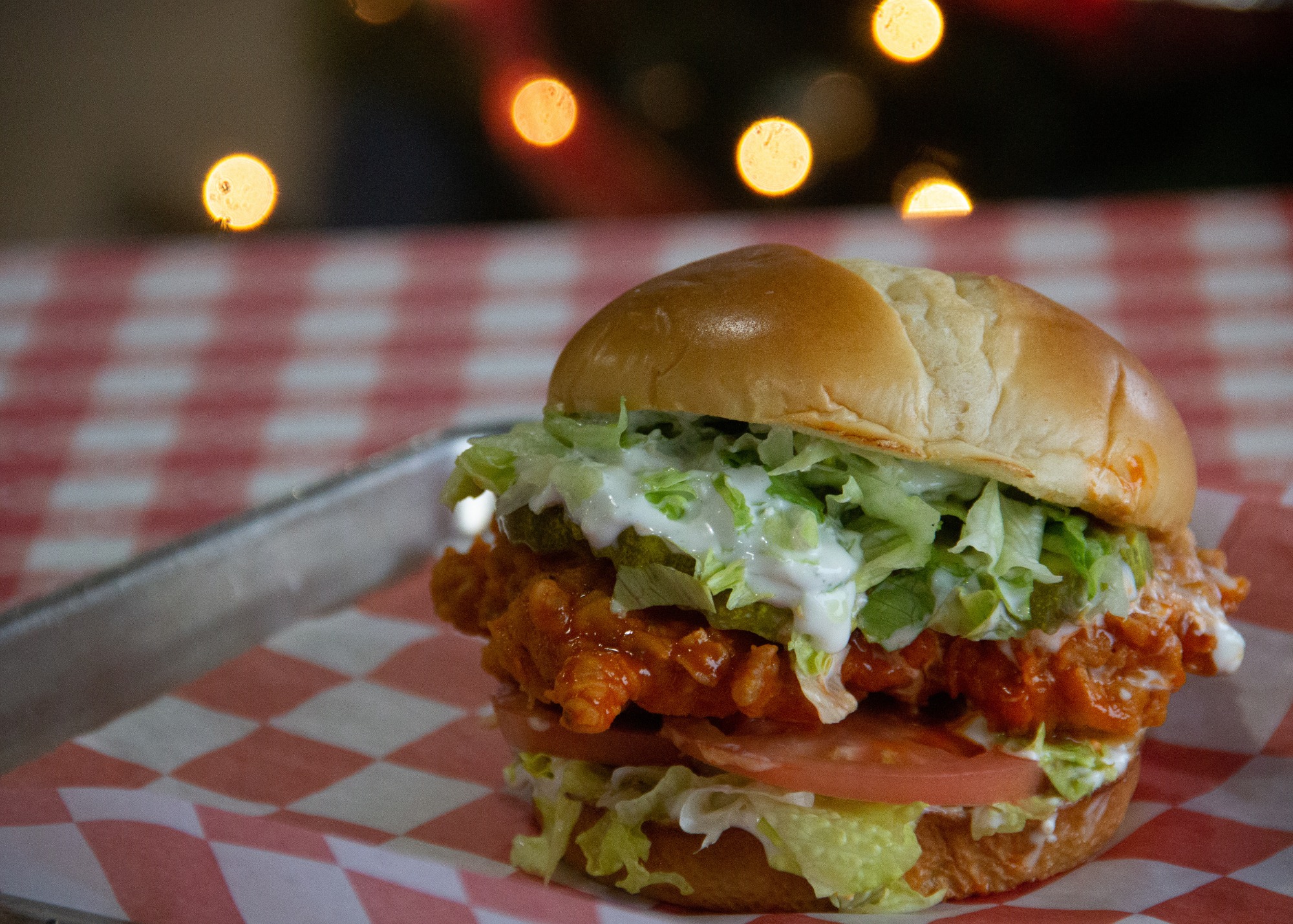 Chicken sandwich shown at right sitting on a red and white tablecloth