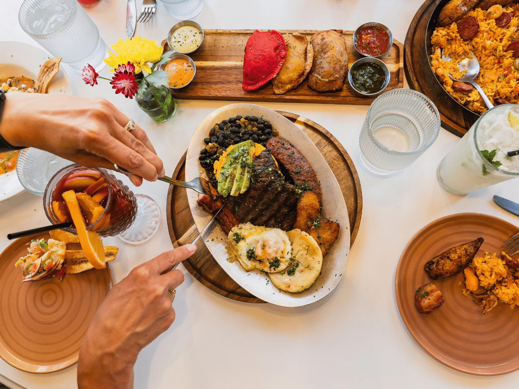 A meal on a table with someone cutting a steak