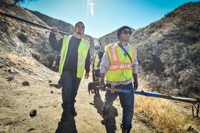 Two men with yellow saftey vests walk in canyon