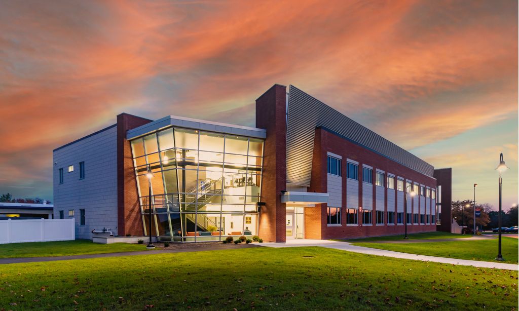 Color rendering of modern brick and glass building lit up at sunset