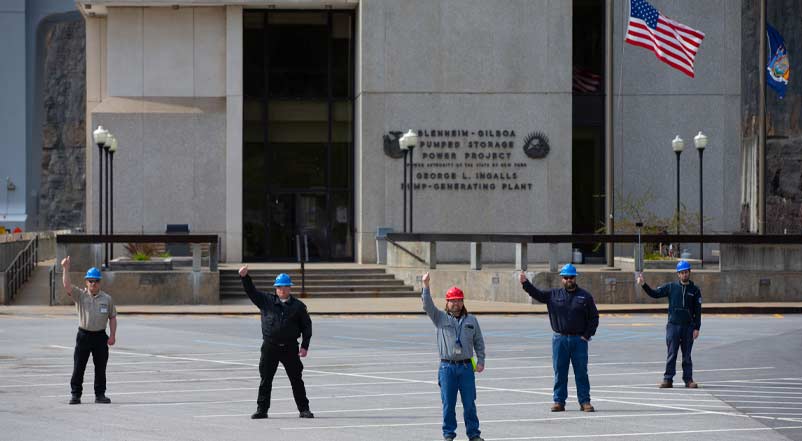 Men in hard hats stand in solidarity in front of building