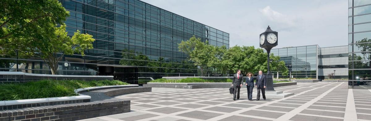 Three lawyers walking in courtyard between glass buildings