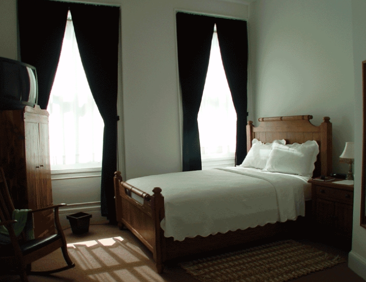 Bedroom with tall windows and bed with wooden bedframe