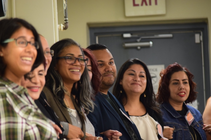 Closeup of people with linked arms smiling