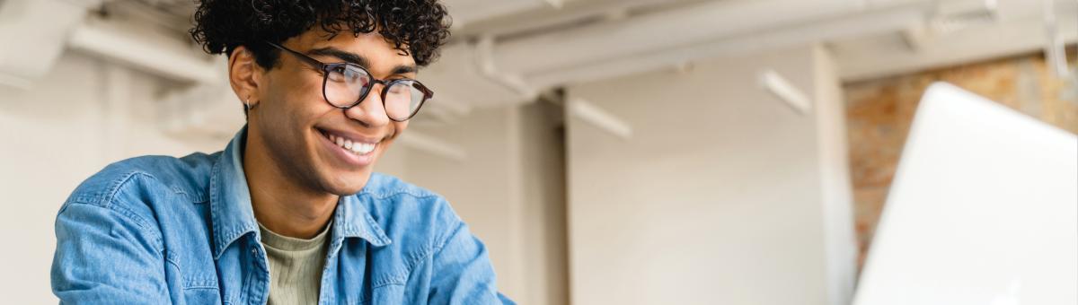 Young man smiling, using computer