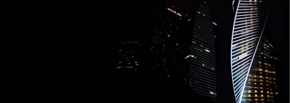 Dark sky with skyscrapers, one on right is lit up brighter