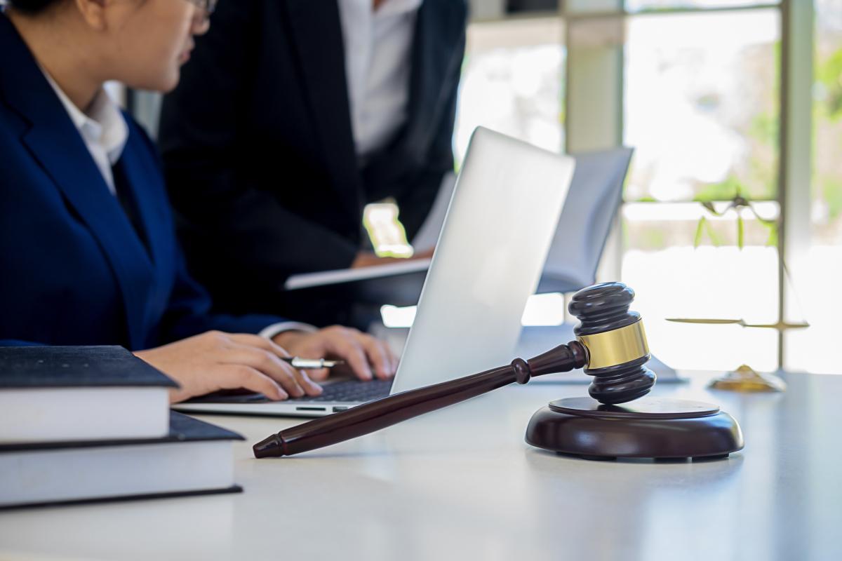 Lawyers on laptops with gavel in front of desk