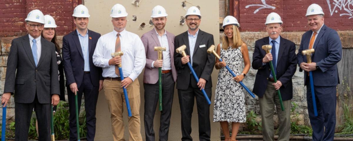 Men and women in hard hats with shovels at groundbreaking