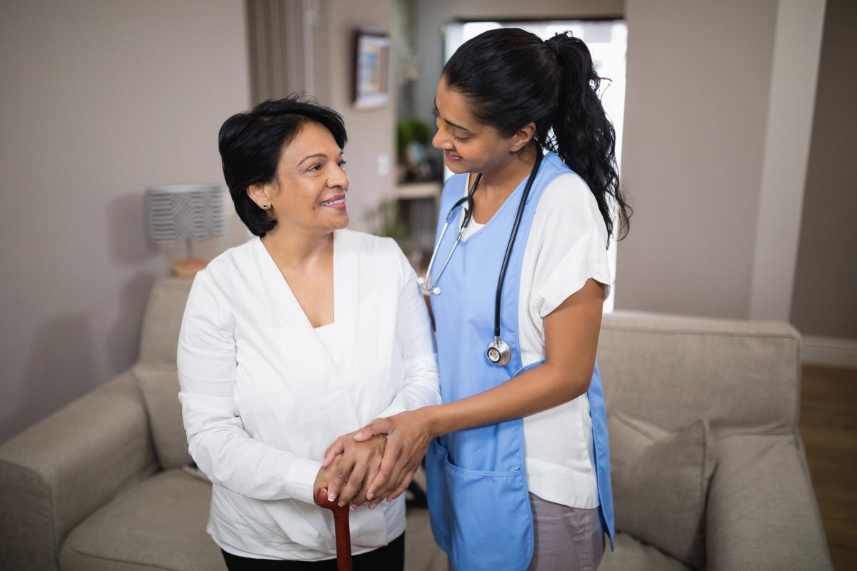 Patient and nurse in front of couch in home