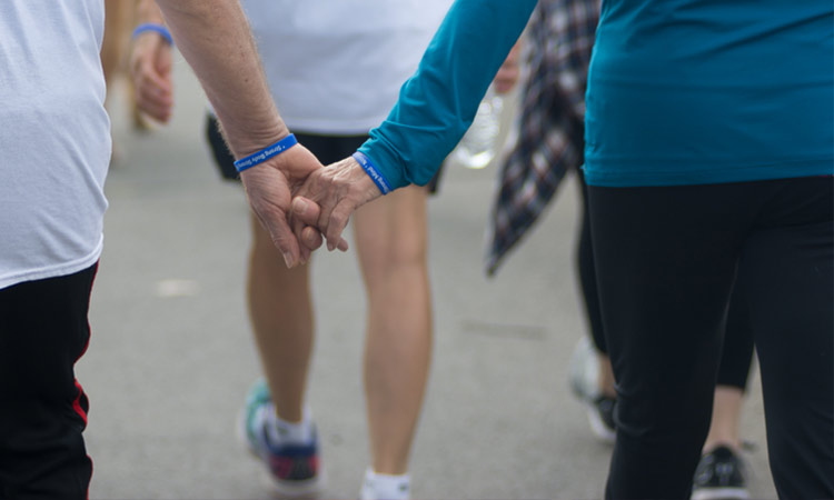 People walking for a cause with blue bracelets on and holding hands