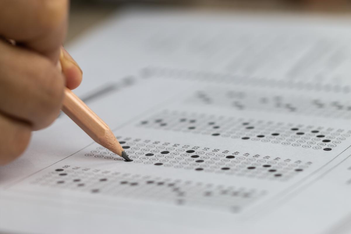 Hand holding pencil filling in test answers