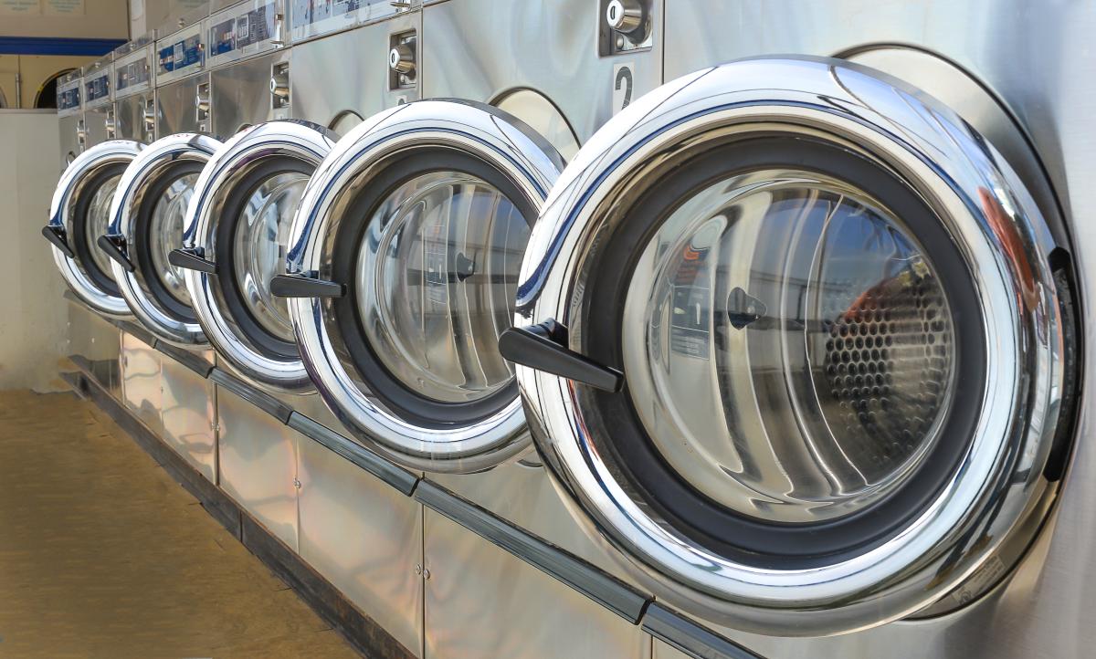Row of commercial washing machines with doors open