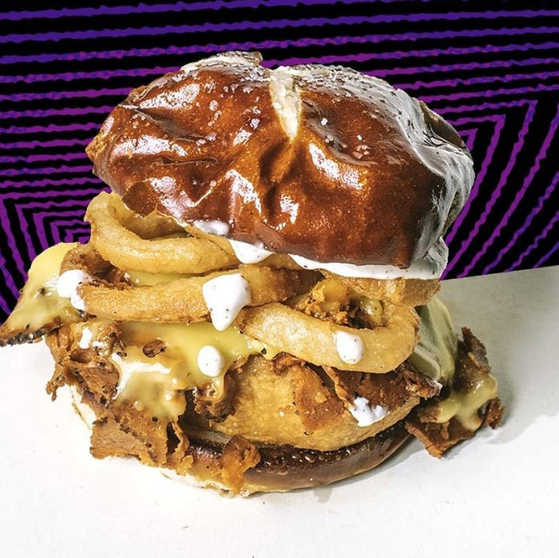 Image of a burger dripping with sauce, in front of a psychedelic illustrated background