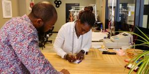 A women writes a receipt for a male customer as they both stand at the counter