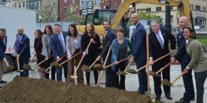 People stand in line and hold shovels at groundbreaking ceremony