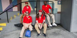 Four men sit on benches in front of stairs and railing