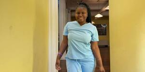 Woman stands in hallway modeling scrubs