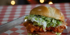 Chicken sandwich shown at right sitting on a red and white tablecloth