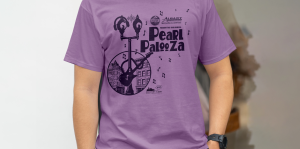 Image of man wearing PearlPalooza tshirt, which is purple and has Pearl Glam mascot on it