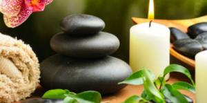 Towel, lit candles and smooth rocks in Asian wooden bowl