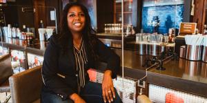 Business owner sits at her bar, smiling at the camera