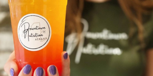 Employee smiles and holds one of Downtown Nutrition Albany's beverages