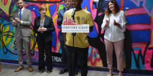 Kevin Skeen at podium with mayor and others clapping behind him at Paint and Pour Up