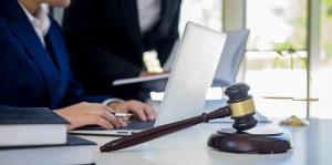 Lawyers on laptops with gavel in front of desk