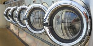 Row of commercial washing machines with doors open
