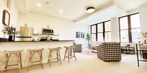 Living room and kitchen shown with island seating, chairs, rug, and couch.