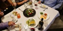 People sit at dining room table full of food and drink