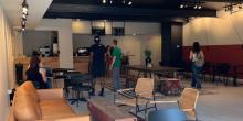 Couches, tables, and chairs inside coffee shop. People wait in line for coffee. 