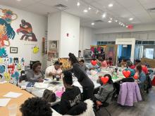 People sit at tables participating in arts workshop