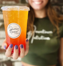 Employee smiles and holds one of Downtown Nutrition Albany's beverages