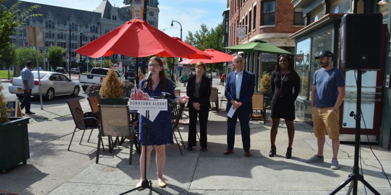 People stand on street for announcement of new bus pass program