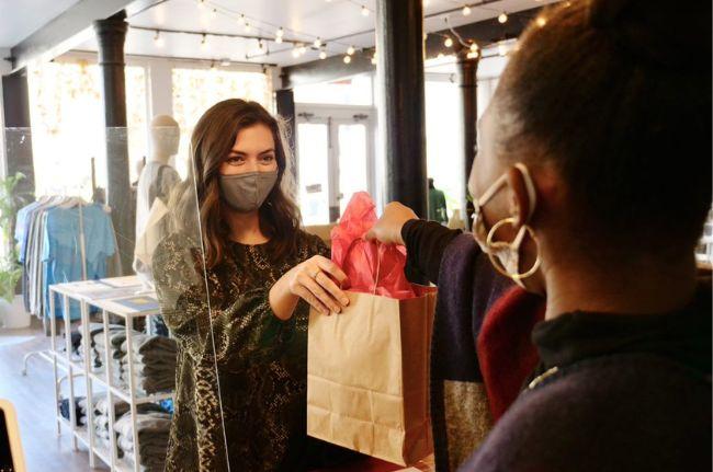 Store clerk handing a brown bag to a customer.