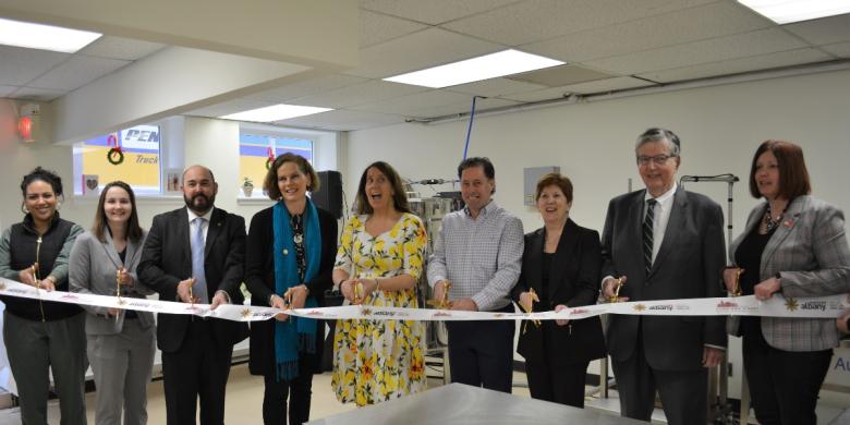 People stand in row and hold scissors at ribbon cutting ceremony