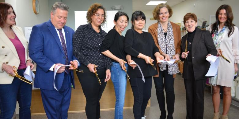 People stand in row and cut ribbon at business celebration of BeAti Acupuncture Wellness Clinic