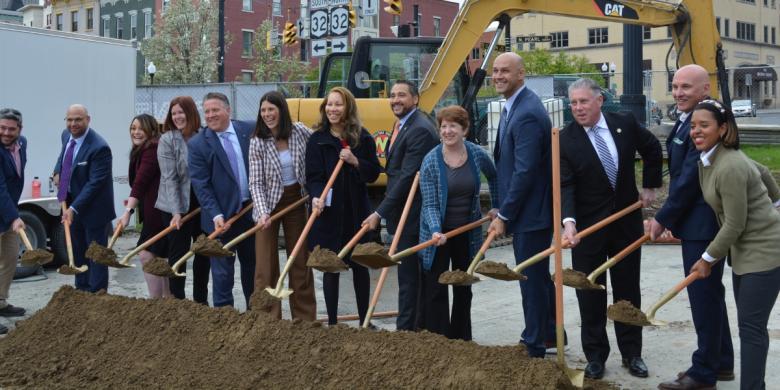 People stand in line and hold shovels at groundbreaking ceremony